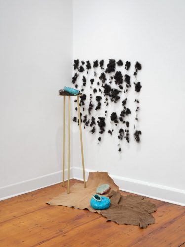 Installation 2026 Die Stelle II Dirty Hair, Ceramics, three leg Table of brass, Leather Skins, Photo Tobias Hübel